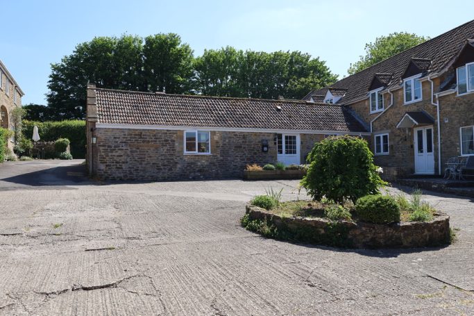Stone building with surrounding greenery and a landscaped area.